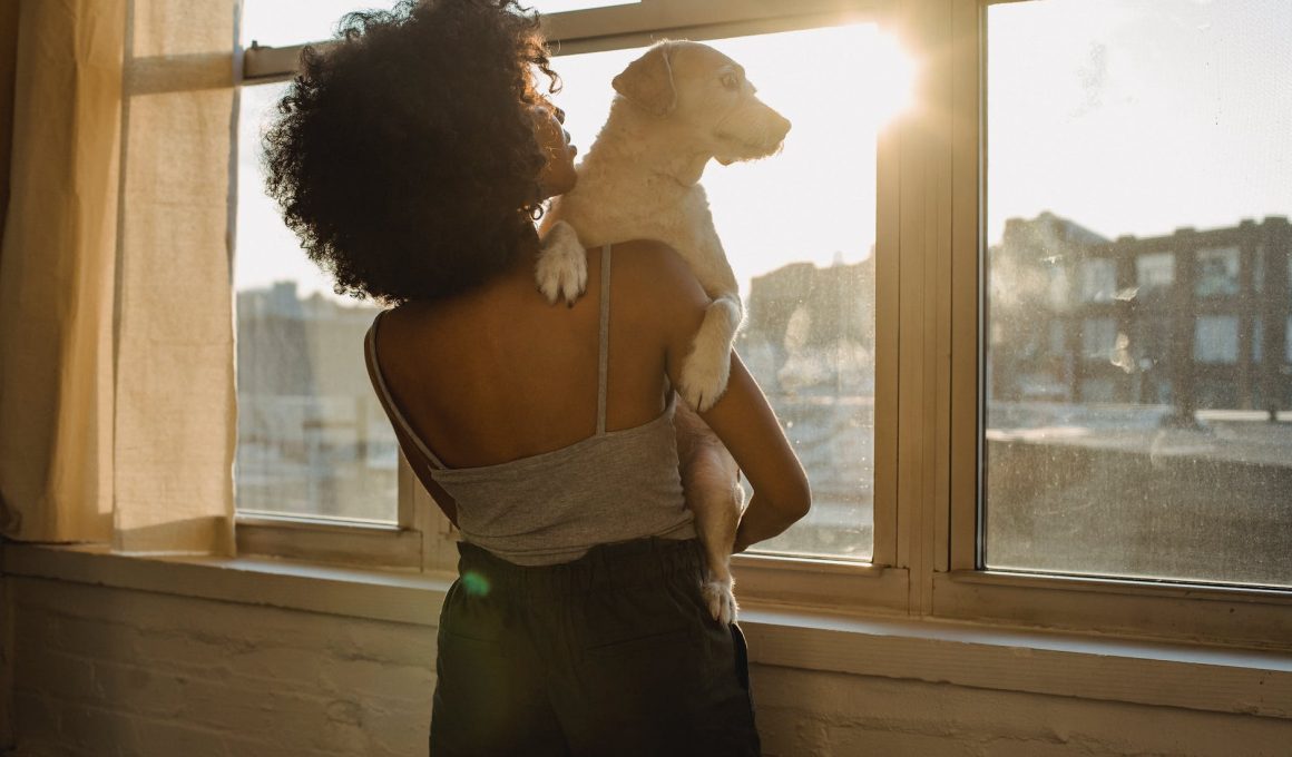 black woman holding dog near window